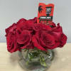 Red roses arranged in a round glass vase with a Trader Joe's tag