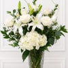 All-white roses, lilies, and a generous cluster of hydrangeas create a serene