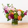 Pale pink and peach roses meet bright orange blooms and vivid green