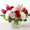 A lush mix of red and white roses with pink lilies takes