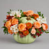 Orange and white flowers arranged in a pumpkin-shaped vase