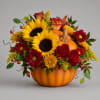 Autumn floral arrangement in a pumpkin container with sunflowers, roses, and mums