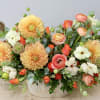 Featuring focal blooms of golden-peach dahlias and layer upon layer of coral