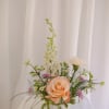 A delicate mini arrangement featuring a soft rose, airy white blooms, and