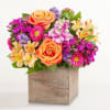 Mixed bouquet of orange roses and colorful flowers in a wooden box