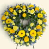 Heart-shaped floral wreath with yellow roses and daisies on a stand