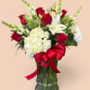 Red roses and white lilies in a glass vase with a red ribbon