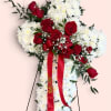 Standing floral spray of white chrysanthemums and red roses with a red ribbon