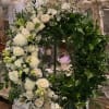 A beautiful wreath adorned with white and ivory roses, lilies, stock and
