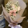 Bouquet of pale pink roses with white baby's breath in pink wrapping