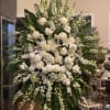 Large white floral standing arrangement with roses, lilies, and cascading blooms