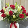 A timeless floral arrangement featuring fresh red roses, fragrant white lilies, baby's