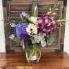 Mixed bouquet in a clear glass vase with purple, white, and pink blooms