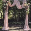 Pink draped wedding arch with pastel floral arrangements