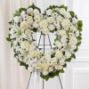 White floral heart wreath on a black stand with a ribbon