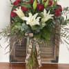 Red roses and white lilies in a clear glass vase with a ribbon