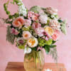 Pastel bouquet of roses, ranunculus, and mixed blooms in a glass vase