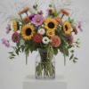 Mixed bouquet of sunflowers, daisies, and zinnias in a clear glass vase