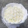 Bouquet of white roses wrapped in white paper with a sheer ribbon