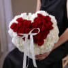 Heart-shaped bouquet of red roses and white flowers with a white ribbon
