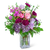 Pink and lavender roses with purple carnations in a clear glass vase