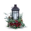 Black lantern with a white candle surrounded by red berries and greenery
