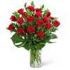 Red roses arranged in a clear glass vase with broad green leaves