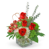 Red roses and pink flowers in a clear square vase