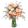 Peach and pink roses with carnations in a clear glass vase