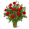 Red roses arranged in a clear glass vase with mixed greenery
