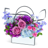 Mixed bouquet in a white handled basket with pink roses and blue flowers