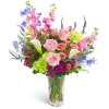 Mixed bouquet of pink roses, calla lilies, and blue flowers in a clear vase