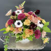 Mixed bouquet of chrysanthemums, carnations, and anemones in a white vase