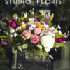 Mixed bouquet of pink roses, lilies, and white hydrangea in a glass vase