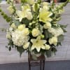 White lilies and roses arranged in a tall vase with greenery