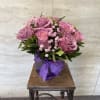 Pink roses in a purple vase with a ribbon bow