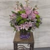 Pink roses and lavender flowers arranged in a purple vase