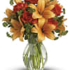 Arrangement of orange lilies and red-orange roses in a clear glass vase