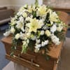 White lilies, roses and chrysanthemums arranged in a low, elegant casket spray