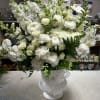 White floral arrangement in a white vase with a sheer ribbon