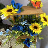 Wooden tiered floral display with sunflowers, blue flowers, and a butterfly