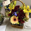 Basket arrangement with yellow lilies, burgundy mums, and peach gerbera daisies