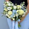 Handheld bouquet of white and pale yellow flowers with blue accents and ribbon