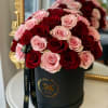 Pink and red roses arranged in a black hat box