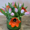Pink and orange tulips arranged in a green glass vase