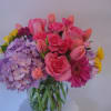 Mixed bouquet of pink roses, tulips, hydrangeas, and a gerbera daisy in a glass vase