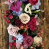 Vertical floral arrangement with roses, orchids, and pale anemones