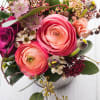 Ranunculus, roses and waxflower in shades of purples, corals and pinks.