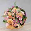 Bouquet of pink and peach flowers wrapped in orange and purple paper