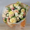 Bouquet of peach roses and pale yellow dahlias wrapped in cream and orange paper